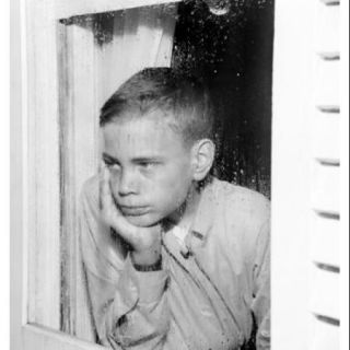 Sad boy looking through window Poster Print (18 x 24)
